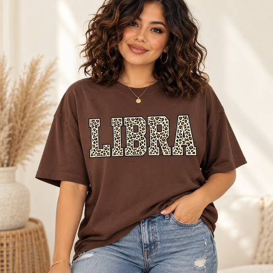 Libra leopard zodiac graphic tee modeled by a curly-haired Latina woman
